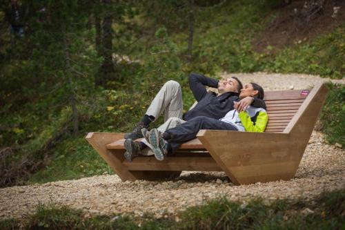 a man and woman laying on a wooden bench at Gasthof Specker in Obereggen