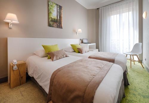 a hotel room with two beds and a chair at Hôtel La Villa Tosca in Cannes