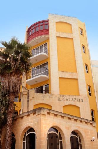 a yellow building with a palm tree in front of it at Il Palazzin Hotel in St Paul's Bay