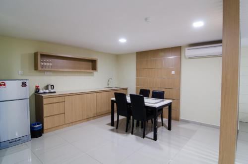 a kitchen with a table and chairs and a refrigerator at Mornington Hotel Sitiawan in Sitiawan