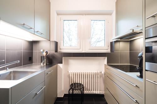 a kitchen with white cabinets and a sink at Appartements Hofquartier in Lucerne