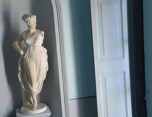 Una estatua de una mujer parada al lado de una puerta en Palazzo Sciacca, en Patti