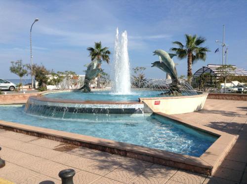 une fontaine dans un parc avec des palmiers en arrière-plan dans l'établissement Le Vina del Mar Bloc B, à Menton