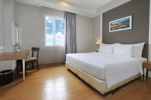 1 dormitorio con 1 cama blanca grande y escritorio en Pranaya Boutique Hotel, en Serpong