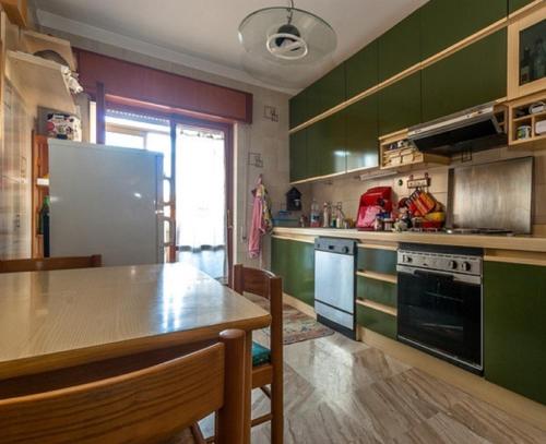 eine Küche mit grünen Schränken und einem Holztisch in der Unterkunft Apartment Trapani in Trapani