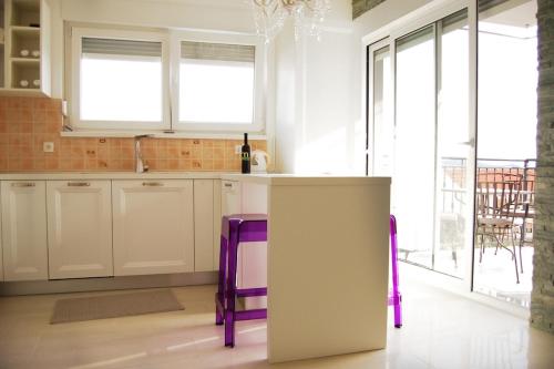 a kitchen with white cabinets and purple stools at Good Spirit in Trogir