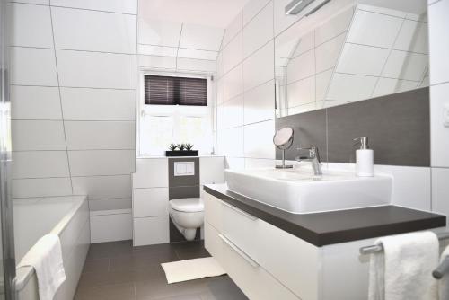 een witte badkamer met een wastafel en een toilet bij Ferienwohnung Brigitta in Hambühren