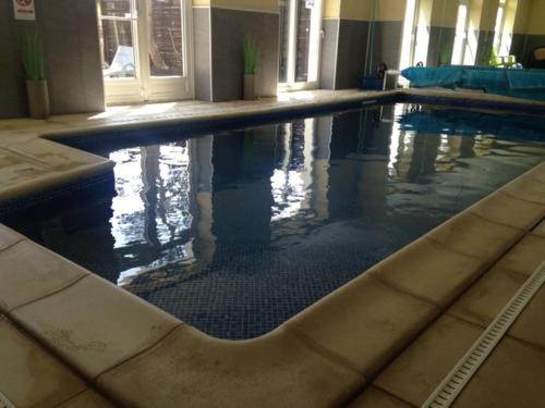 a large swimming pool in a large building at Auberge De La Luzerne in Bernières-sur-Mer