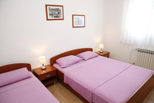 a bedroom with two beds with purple sheets and lamps at Apartmani Šprljan in Vodice