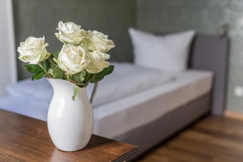 un vase blanc avec des roses blanches assis sur une table dans l'établissement Villa Stern, à Oldenbourg