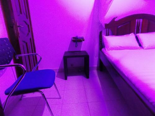 a room with a purple room with a bed and chairs at Star Royal Motel Kitebi Kampala in Kampala