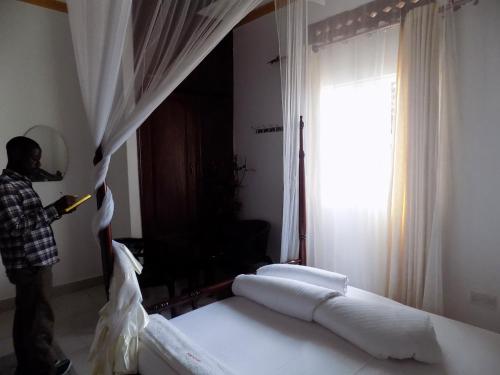 a man standing in a bedroom with two beds at Star Royal Motel Kitebi Kampala in Kampala