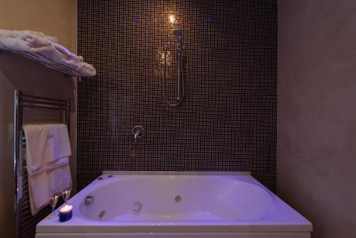 a bath tub in a bathroom with black tiles at Palazzo Ferraioli - Hotel & Wellness in Atrani