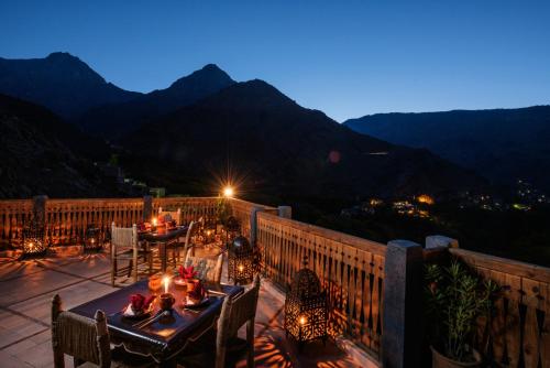 a patio with tables and chairs and mountains at night at Le Village du Toubkal in Imlil