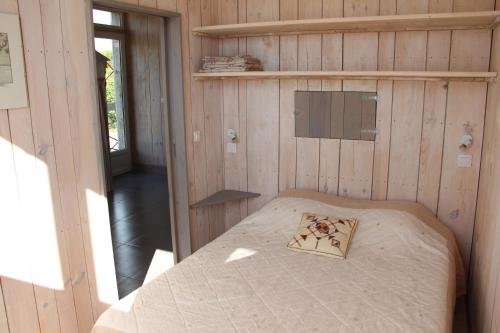 a small bedroom with a bed in a wooden wall at Le grenier a sel in Marennes