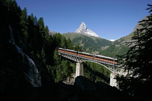 a train on a bridge with a mountain in the background at Haus Alpenschloss in Zermatt