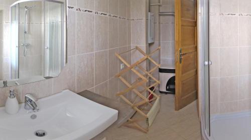 a bathroom with a sink and a shower with a mirror at Tarjányi Vendégház in Recsk