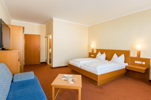 a hotel room with a bed and a blue couch at Hotel Stadt Wien in Bad Schallerbach