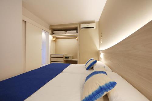 a bedroom with a large bed with blue and white pillows at Son Caliu Apartamentos in Palmanova