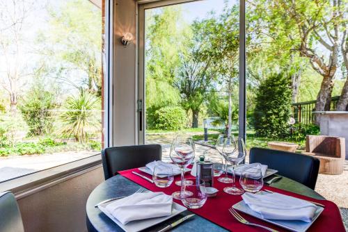 a table with wine glasses and napkins on it at SOWELL HOTELS Domaine de la Petite Isle in LʼIsle-sur-la-Sorgue