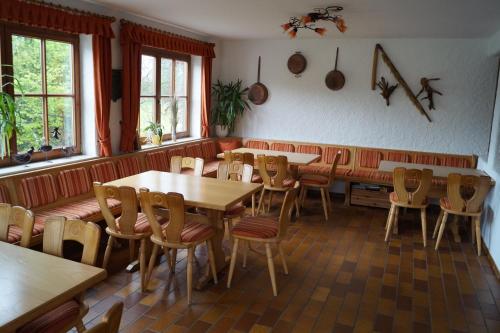 ein Restaurant mit Holztischen, Stühlen und Fenstern in der Unterkunft Gästehaus zur Mühle Dehm in Friedrichshafen