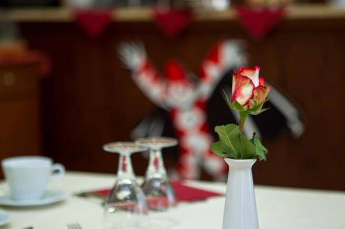 a red rose in a white vase on a table at Hotel Playa in Viareggio