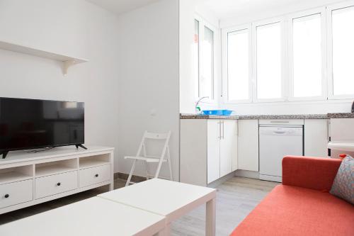 a white living room with a tv and a couch at Suncity Flat Victoria in M&aacute;laga