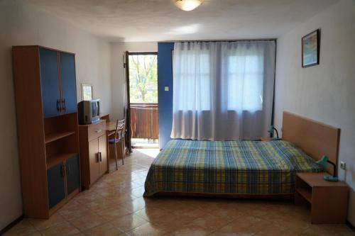 1 dormitorio con 1 cama, TV y ventana en Guestrooms Ross, en Veliko Tŭrnovo