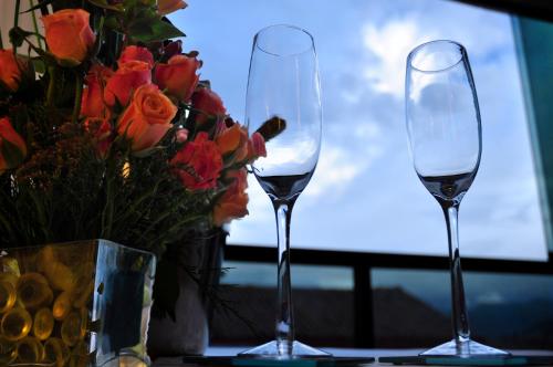 two wine glasses sitting on a table next to a vase of flowers at Kapac Inn Hotel in Cusco