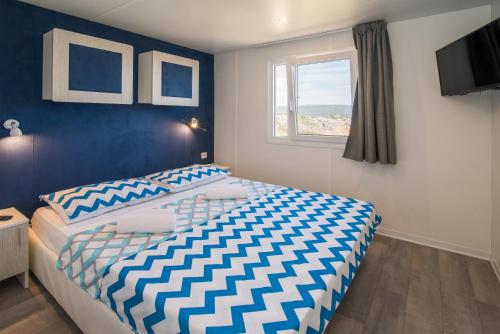 een slaapkamer met een bed met een blauwe muur bij Mobile Homes Residence Ulika in Krk