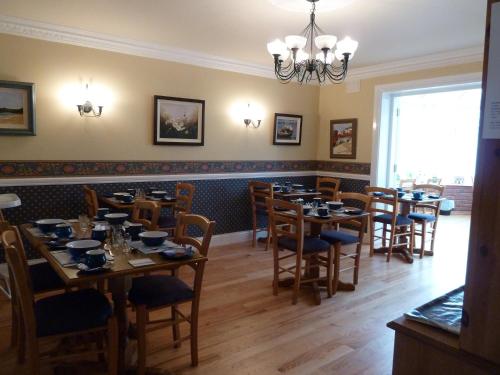 a dining room with tables and chairs and a chandelier at Westwinds Guestlodge in Galway