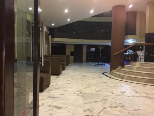 a lobby with couches and stairs in a building at Hotel Pooja International in Dāvangere