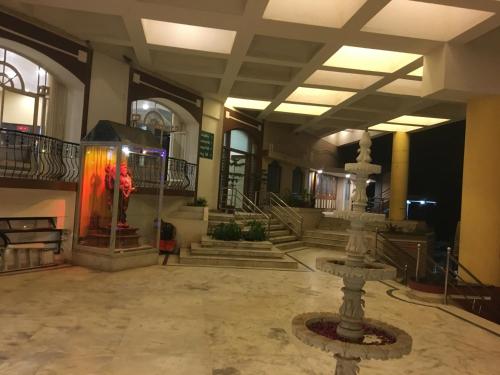 a lobby with a fountain in the middle of a building at Hotel Pooja International in Dāvangere