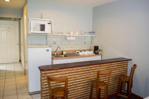 a kitchen with a counter with chairs and a microwave at Apartotel Tairona in San Pedro
