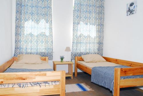 two beds in a room with blue and white curtains at Maison Blanche Kyiv city center in Kyiv