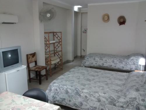 Habitación de hotel con 2 camas y TV en Departamentos Urquiza en Salta