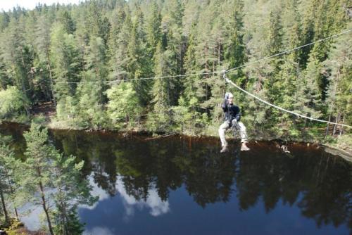 a man on a zip line over a body of water at Tivedens Hostel-Vandrarhem in Karlsborg