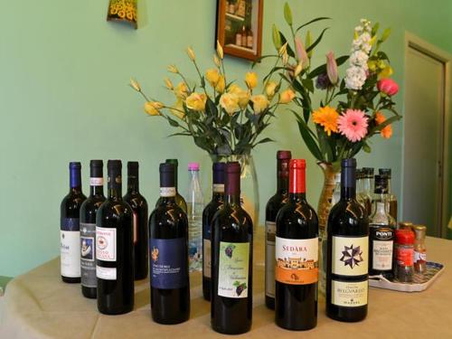a group of wine bottles on a table with flowers at Pensione Andrea in Chianciano Terme