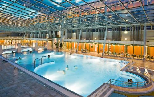 een groot binnenzwembad met mensen erin bij Das Gutenbrunn Thermen & Sporthotel in Baden