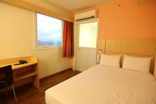 a bedroom with a bed and a desk and a window at Samba Itaboraí in Itaboraí