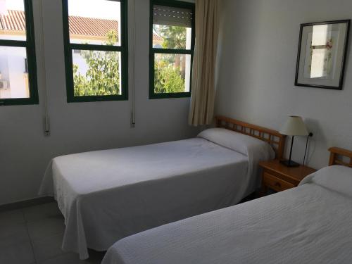 two beds in a room with two windows at Apartamentos Torrelaguna in Vera