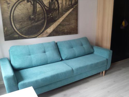 a blue couch in a living room with a bike on the wall at Studio Nowy Świat in Warsaw
