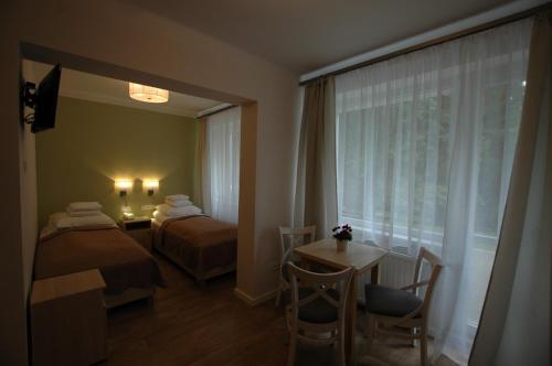 ウストロンにあるZNP ZG Dom Wypoczynkowy Nauczycielのベッド2台、テーブル、窓が備わるホテルルームです。
