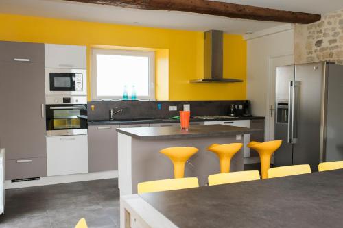 une cuisine avec tabourets jaunes et comptoir dans l'établissement Maison Bayeux 4 chambres, à Cristot