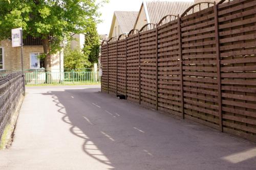 une clôture en bois à côté d'un trottoir et d'une route dans l'établissement Turnė Guest House, à Šiauliai