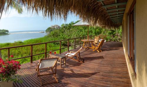 a deck with chairs and a table with a view of the water at Villa Playa Tayrona, Los Naranjos in Los Naranjos
