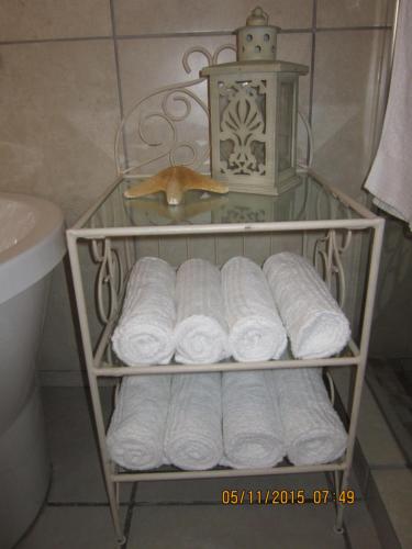 un porte-serviettes avec un tas de serviettes dans une salle de bain dans l'établissement Twilight Cottage, à Plettenberg Bay