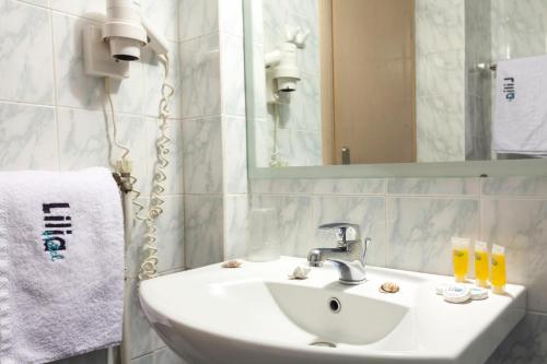a white sink sitting under a mirror in a bathroom at Lilia Hotel in Piraeus