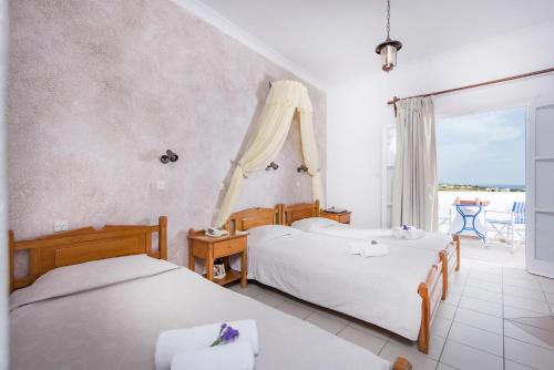 a bedroom with two beds and a balcony at Hotel Olympia in Karterados