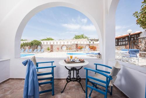 a patio with a table and chairs and a view of a pool at Hotel Olympia in Karterados